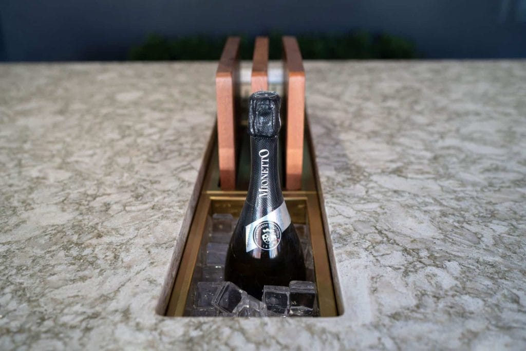 Close-up of a bottle of Prosecco in a built-in ice bucket on a granite countertop.