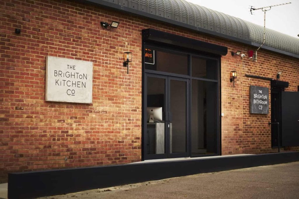 The exterior of The Brighton Kitchen Company building, featuring a brick facade and signs for The Brighton Kitchen Co and The Brighton Bathroom Co.